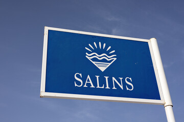 Blue signpost saying Salins from the Pink Lake Of Torrevieja, Salinas de Torrevieja in front of a blue sky background