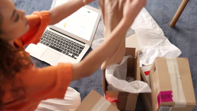 Fashion, ecommerce and small business box with laptop for inventory and packaging organisation. Online shopping, entrepreneur and clothing company woman sorting packages for delivery schedule.