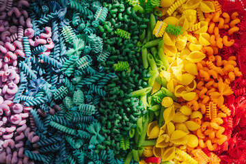 Sensory bin with dried pasta in rainbow colors. Dyed pasta for play and craft activities. Montessori material. Sensory play and learning colors activity for kids.