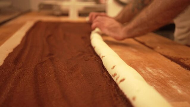 Baker working with handmade pastries in small bakery. Cocoa snail roll, chocolate roll. Closeup video of not staged, authentic moment.