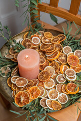 Adventsschale mit Kerze, Eukalyptus und getrockneten Orangenscheiben auf goldenem Teller dekoriert für Weihnachten, minimalistische Dekoration

