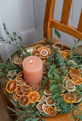 Adventsschale mit Kerze, Eukalyptus und getrockneten Orangenscheiben auf goldenem Teller dekoriert für Weihnachten, minimalistische Dekoration
