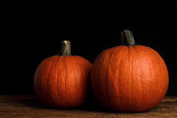 Two large orange whole mature pumpkins on a rustic wooden background, close-up. Concept of Halloween. Free space for text 