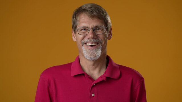 Portrait face of happy smiling mature man expressing joy and laughing with an open mouth. Mature male reacting to funny joke isolated on yellow background.