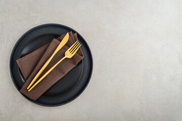 table place setting with black plates and golden cutlery