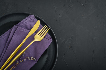  table place setting with black plates and golden cutlery on black  background
