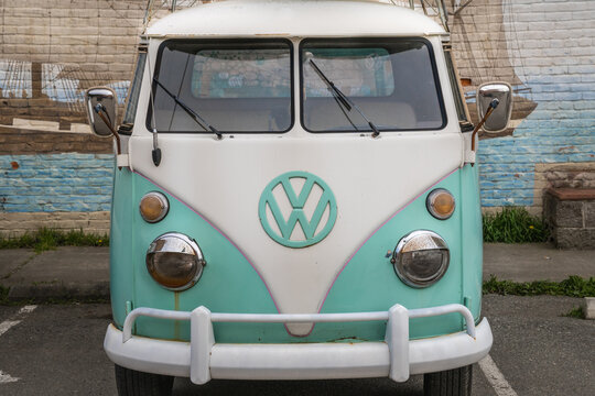 Port Townsend, WA, US-March 25, 2022:  Vintage 1960s blue-green VW kombi camper van or microbus modified as a pick-up with surfboards on roof parked on street.