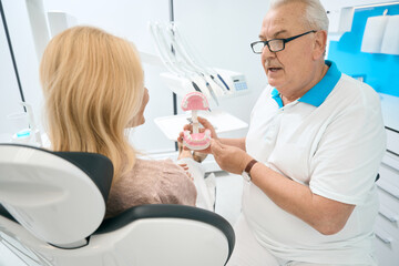 Obraz premium Elderly dentist is talking with female in medical office