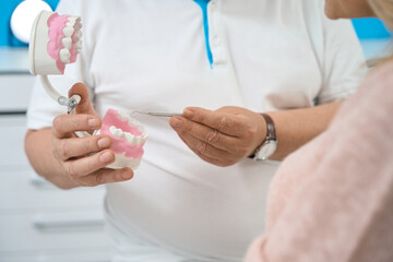 Orthodontist with teeth model and metal equipments in dentist clinic