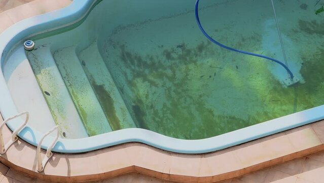 Top view of a Vacuum Cleaner submerged in a dirty swimming pool