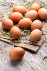 Brown chicken eggs lie on the background of hay and old boards.