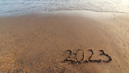 New year 2023 handwritten in the sand surface