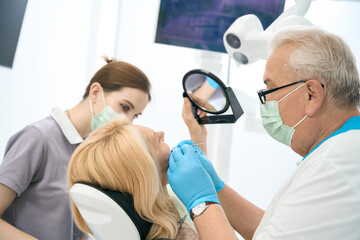 Fototapeta na wymiar Blonde female patient is getting dental check up in medical center