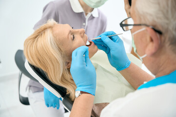 Female patient on the chair is receiving dental check up in stomatology center