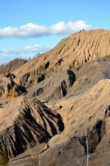 Beautiful vertical natural landscape with a big coal canyon. Scenic mountain landscape on a sunny autumn day. Coal canyon close-up. Brown mountains with a blue sky. Mountain tourism