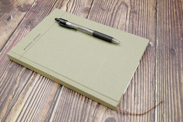 Top view of new personal planner, green color, with a black ballpoint pen placed on top, on old wood background.