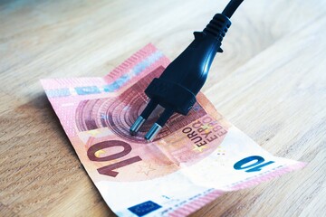 concept of the cost of electricity socket attacking a banknote