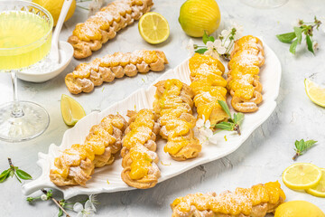 Traditional italian homemade lemon alcohol drink liqueur limoncello with pieces of lemon and rosemary herb on light pink, peach or coral color stone concrete surface