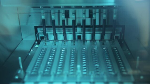 Close-up view of medical laboratory equipment. Glass tubes filled with liquid medicine. Chemical vials inside automatic robot machine. Producing biological weapon in lab. Film grain texture.