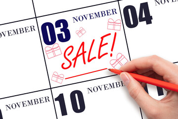 Hand writing text SALE and drawing gift boxes on calendar date November 3. Shopping Reminder