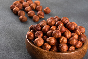 Top view of a bowl full of hazelnuts on dark background