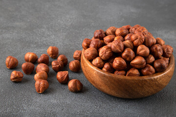 Top view of a bowl full of hazelnuts on dark background