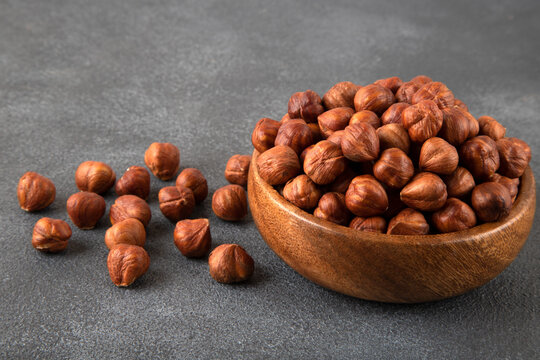 Top view of a bowl full of hazelnuts on dark background
