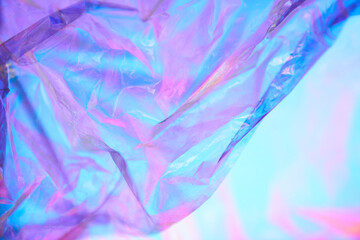 Part of transparent holographic wrinkled mother-of-pearl polyethylene. Holographic colorful plastic film in purple and blue tones. High quality photo