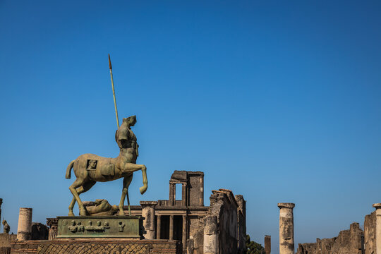 A centaur statue on display in the ruins of Pompeii with a clear blue sky in Italy.