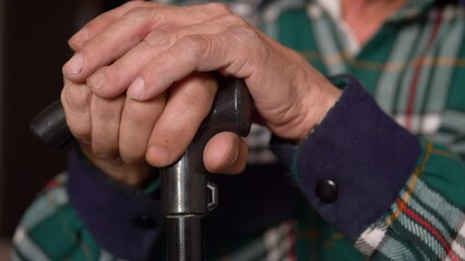 close-up of an elderly man's hand holding a walking stick, selective focus. The hands of a wrinkled old man.a pensioner with a walking stick is sitting. joint problems as you age