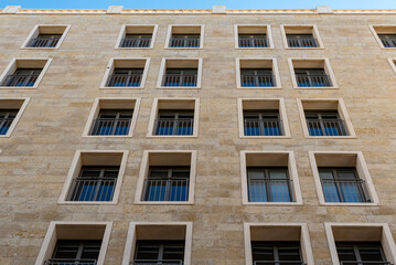 Black long thin rectangular windows in the new building. Many windows dark brown color on the house