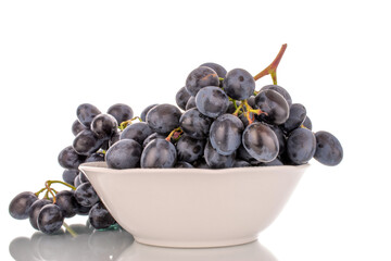 One sprig of sweet black grapes in a ceramic plate, macro, isolated on white background.
