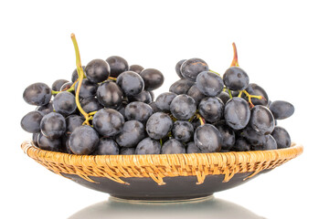 One sprig of sweet black grapes in a ceramic plate, macro, isolated on white background.