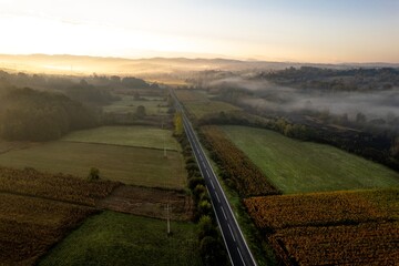 Aerial view of road surrounded by fog, in the morning, near Soceni village, Romania. Captured from above with a drone.