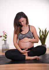 beautiful 30s-40s pregnant woman exercising yoga looking thoughtfully