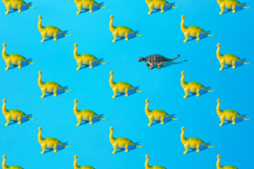 Fototapeta na wymiar Yellow green Brachiosaurus and gray Ankylosaurus plastic toy dinosaur on a blue background. Pattern.