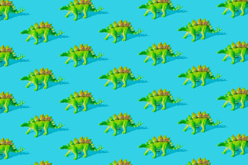 Fototapeta na wymiar Green Stegosaurus dinosaur toy on a blue background. Pattern.