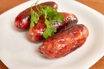 Fried sausages on a white plate.
