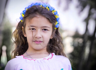 Ukrainian Schoolgirl in a wreath and embroidered shirt and with patriotic flowers against the war in Ukraine