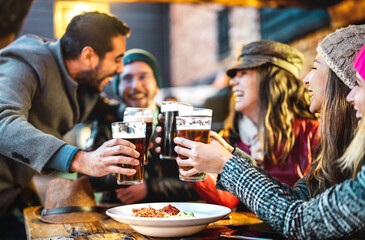 Friends having fun drinking beer at restaurant garden on winter time - People lifestyle concept at...