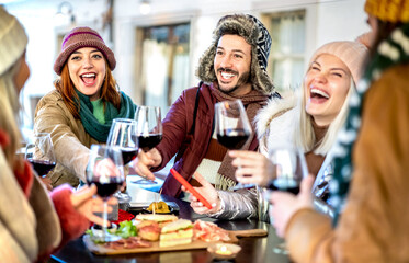Young people toasting red wine at restaurant garden - Happy friends having fun together at winery bar on winter time - 538410408