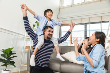 Happy dad lifting excited daughter girl playing airplane with flying open hand in living room.Asian...