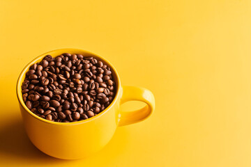 Obraz premium Cup of freshly brewed roasted coffee beans on yellow background