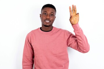 young handsome man wearing pink sweater over white background showing and pointing up with fingers number three while smiling confident and happy.