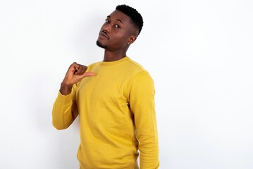Closeup of cheerful young handsome man wearing yellow sweater over white background looks joyful,...