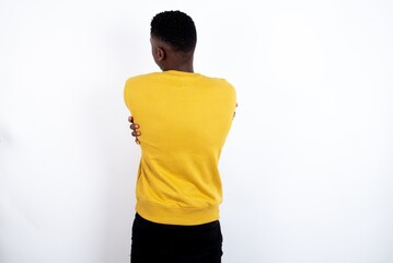 young handsome man wearing yellow sweater over white background hugging oneself happy and positive from backwards. Self love and self care.