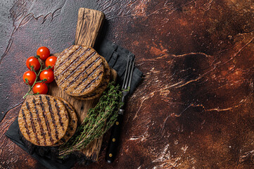 BBQ Grilled plant based meat burger patties,  vegan cutlets on wooden board with herbs. Dark...