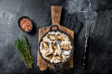 Seafood Risotto with clams in a skillet. Black backgroud. Top view