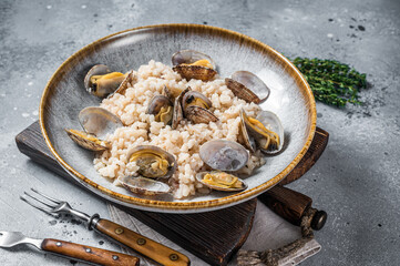 Italian Risotto with clams in a rustic plate with herbs. Gray backgroud. Top view