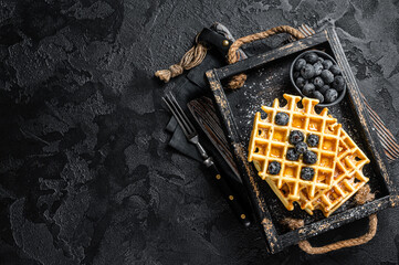 Belgian homemade waffles with blueberry and Syrup . Black background. Top view. Copy space